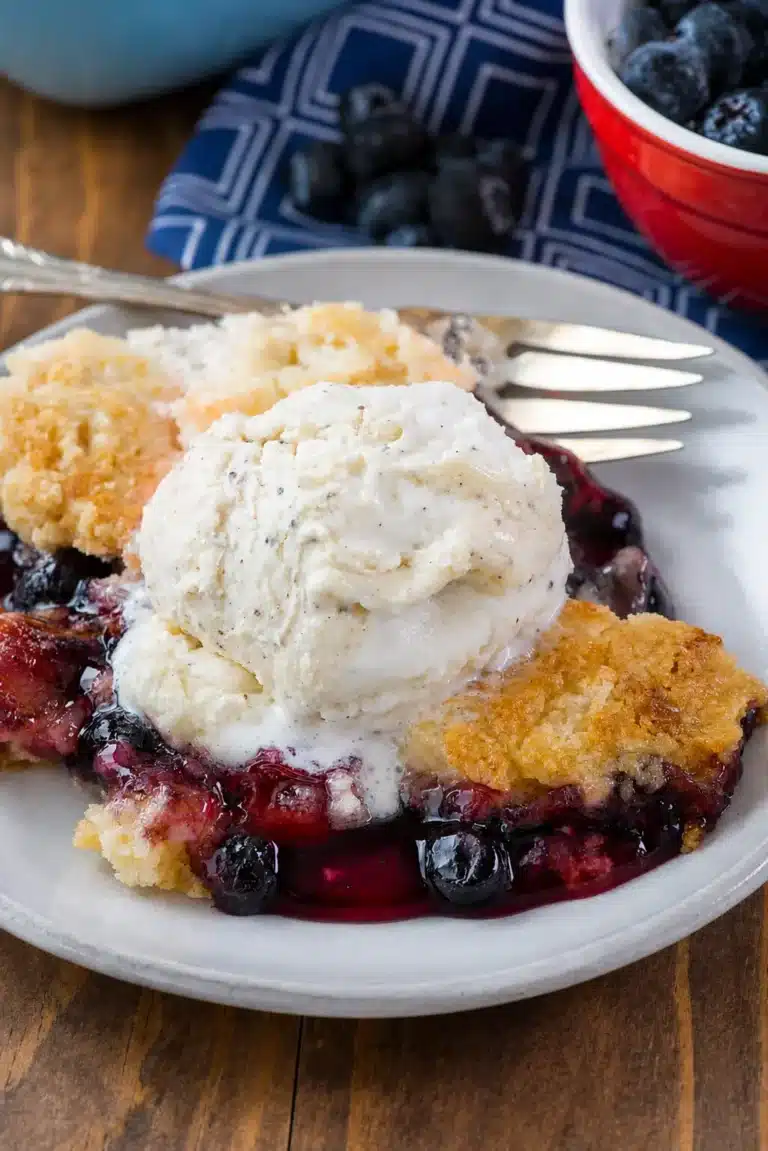 Cherry Berry Dump Cake served warm with vanilla ice cream in a white bowl.