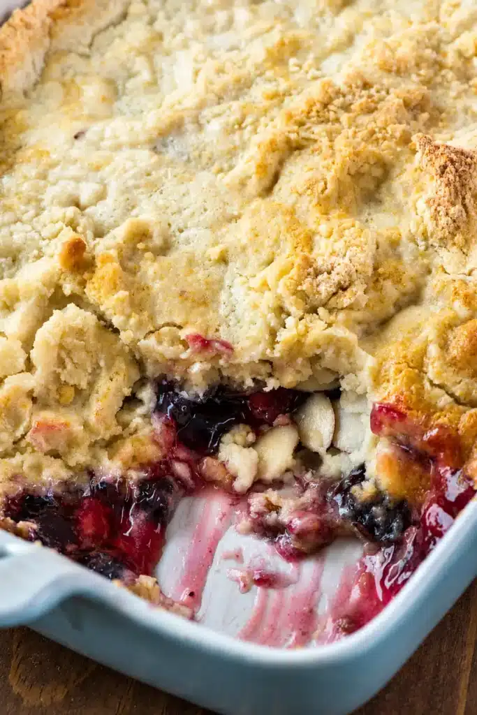Warm Cherry Berry Dump Cake served on a plate with whipped cream.
